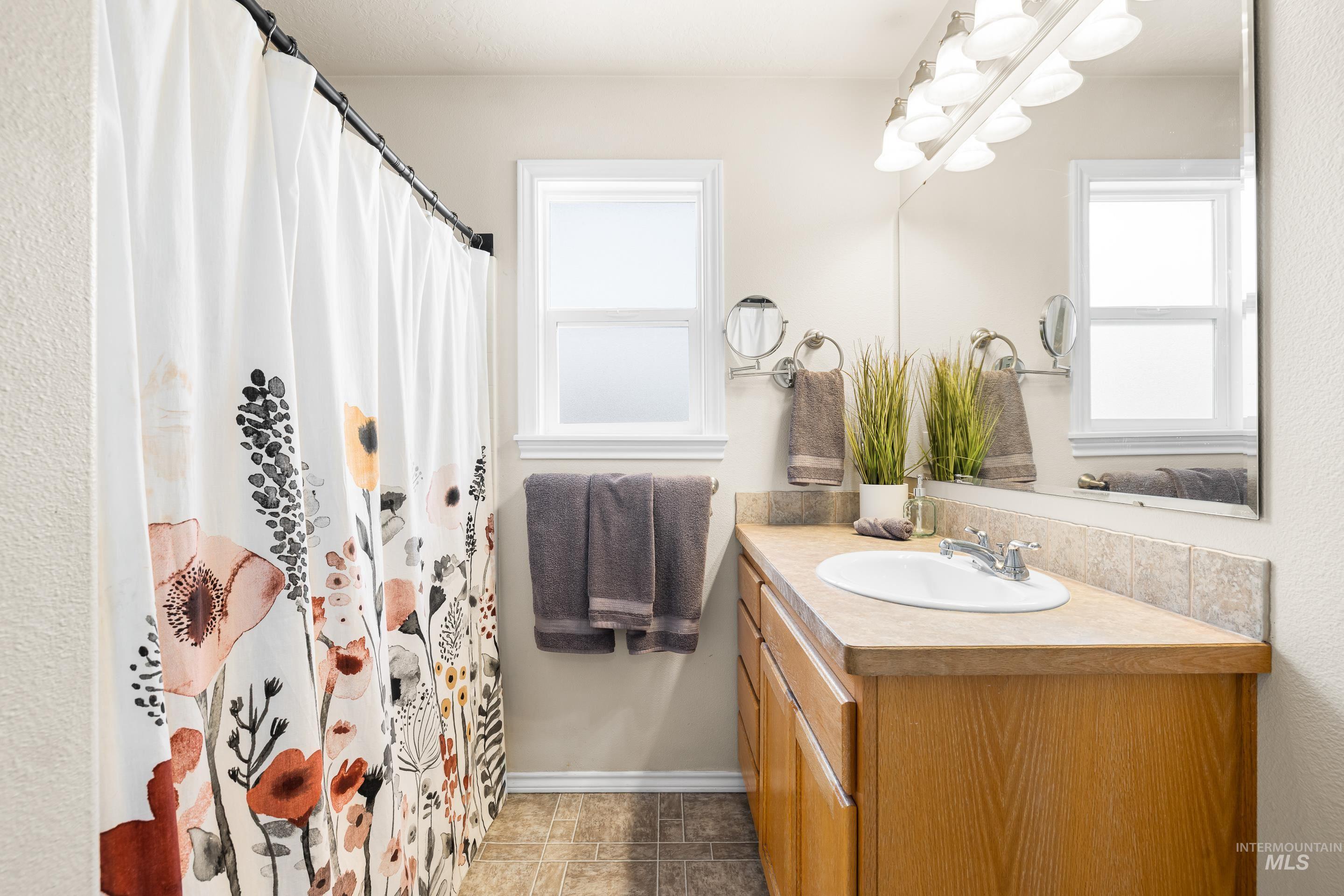 Bathroom with vanity, healthy amount of natural light, a shower with curtain, and light tile patterned floors