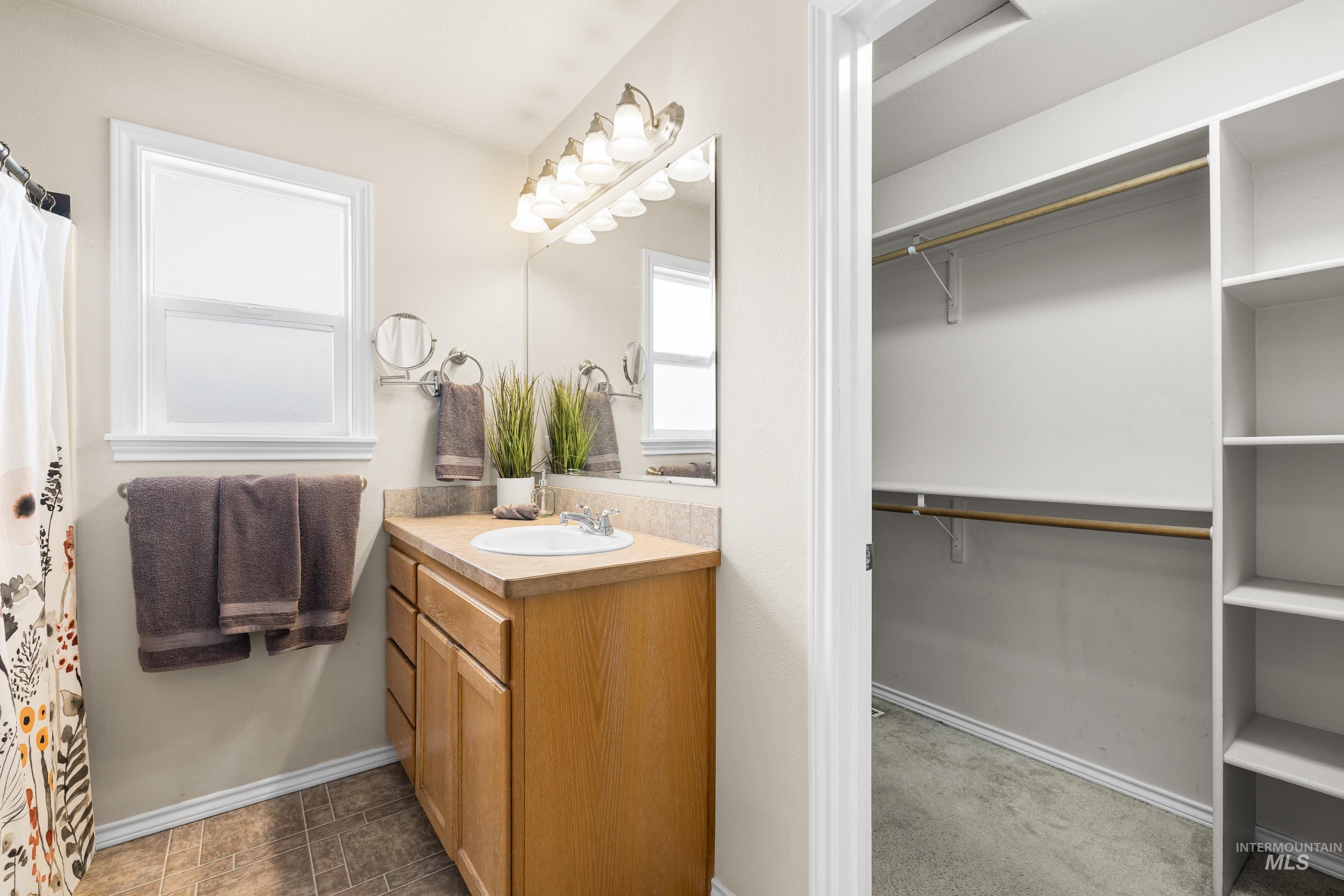Bathroom featuring vanity, a spacious closet, and curtained shower