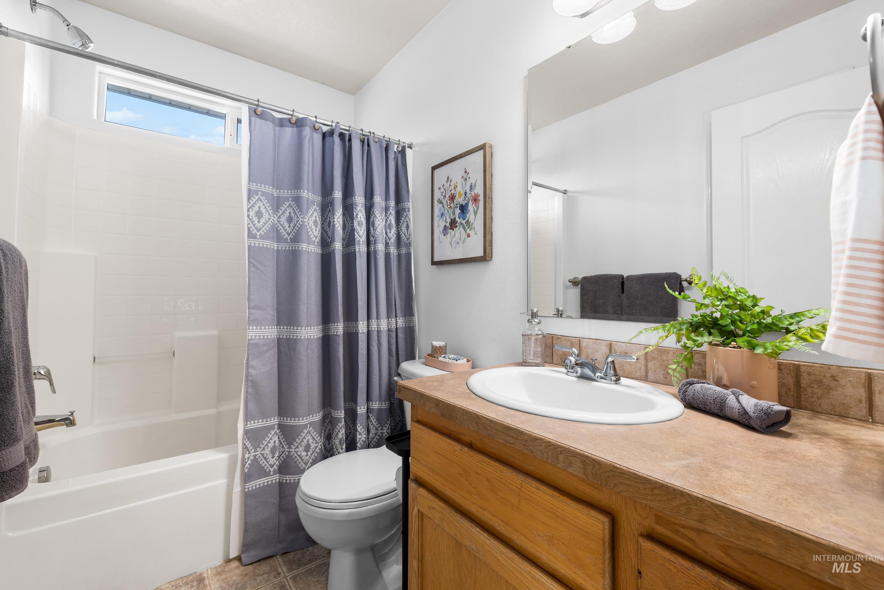 Full bathroom featuring shower / bath combination with curtain, vanity, dark tile patterned floors, and decorative backsplash