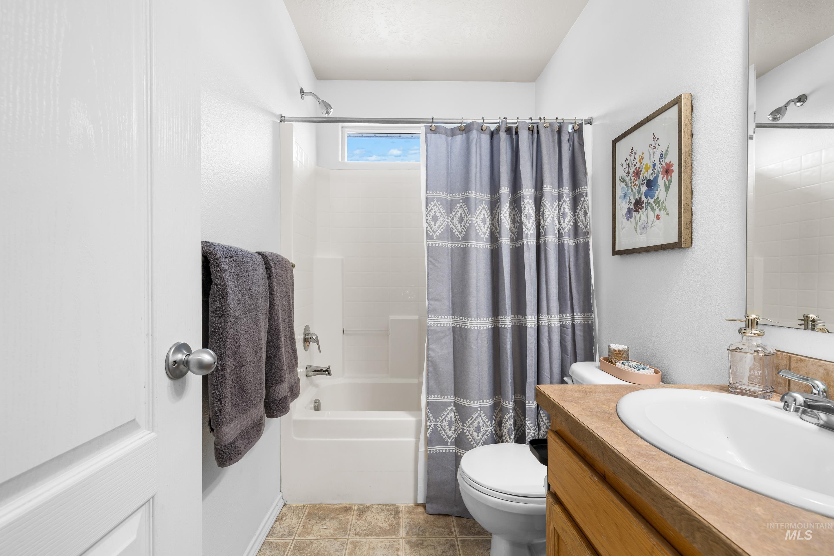 Full bathroom featuring shower / bath combo with shower curtain, vanity, and light tile patterned floors