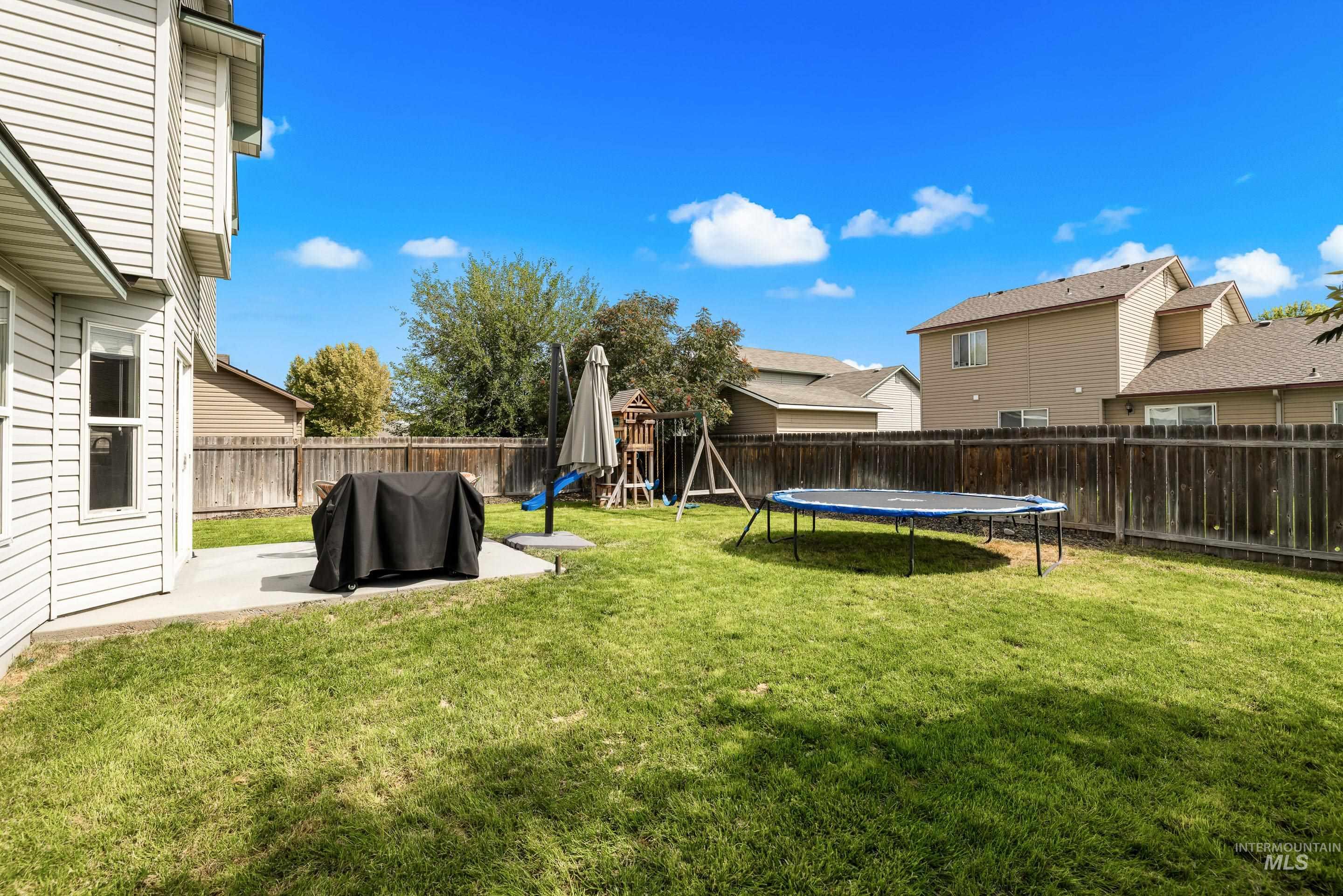 Fenced backyard with a patio, a playground, and a trampoline