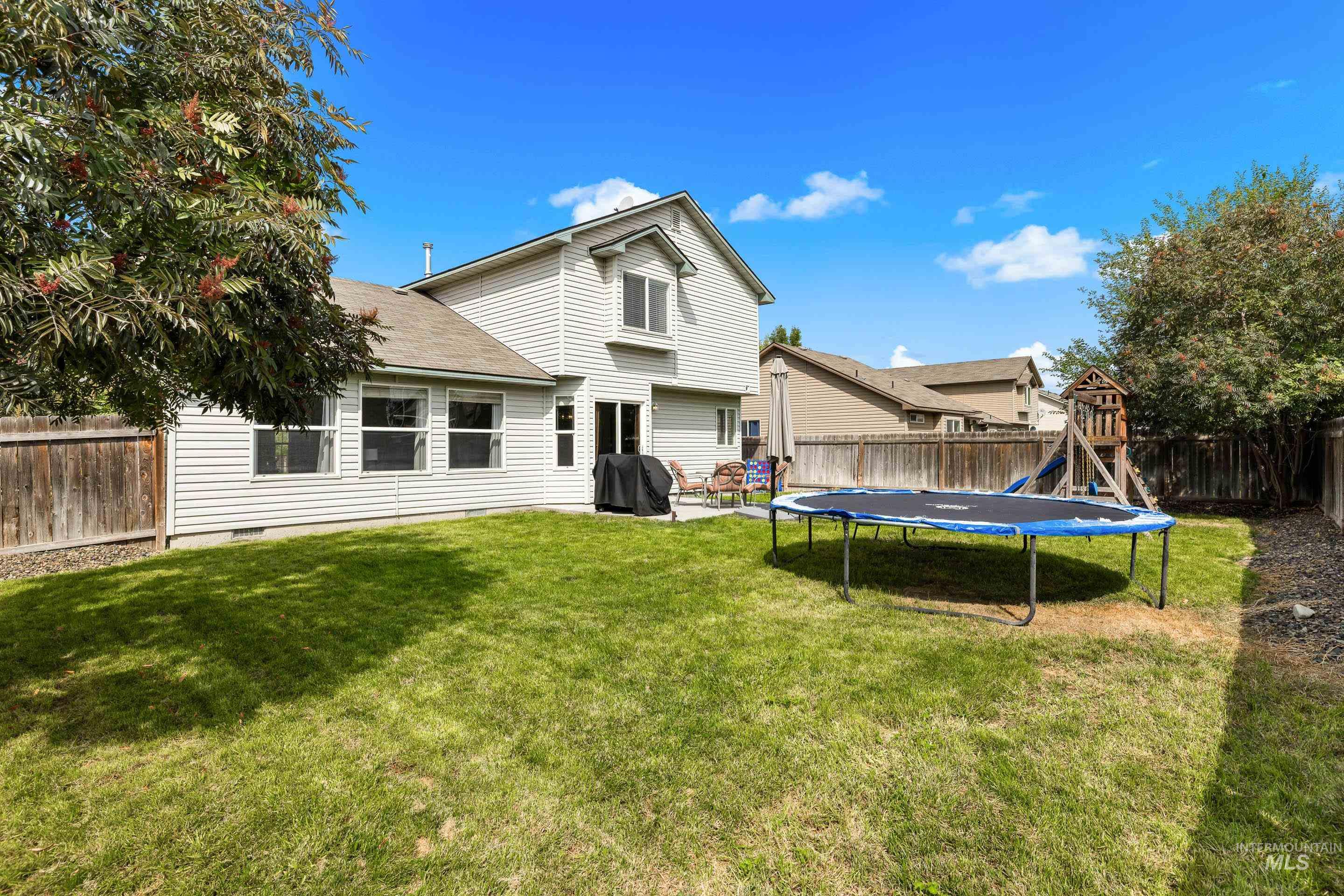 Back of house featuring a fenced backyard, roof with shingles, a trampoline, and a patio area