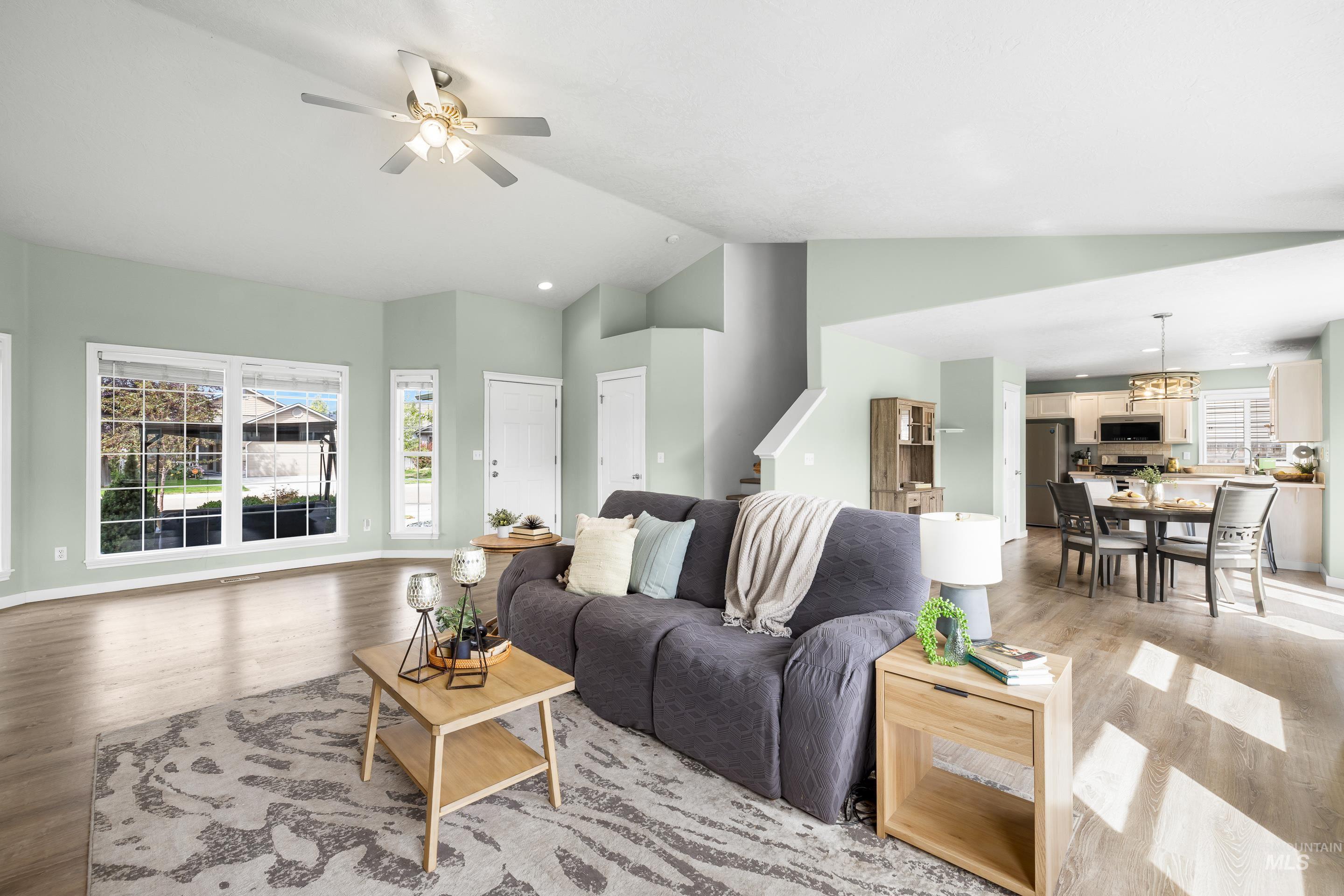 Living room featuring light wood-type flooring, high vaulted ceiling, a ceiling fan, and recessed lighting