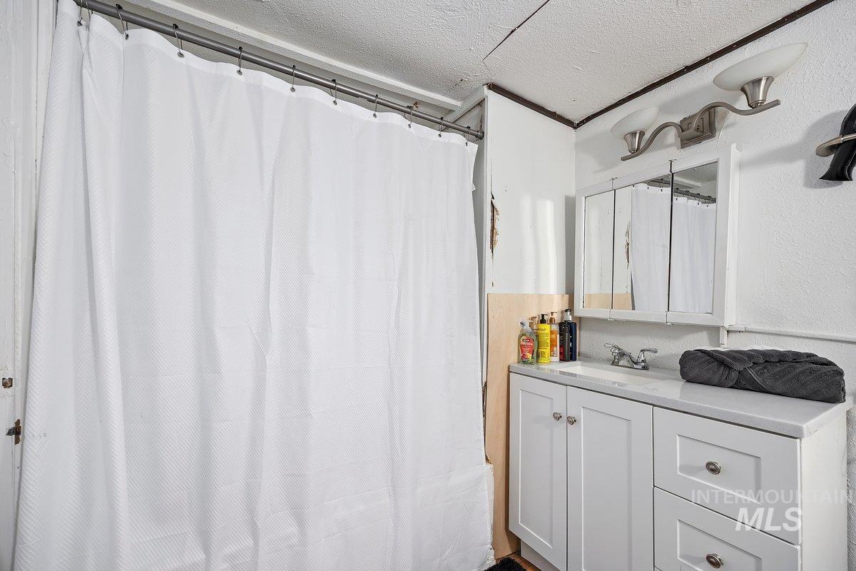 Bathroom with vanity, a textured ceiling, and curtained shower