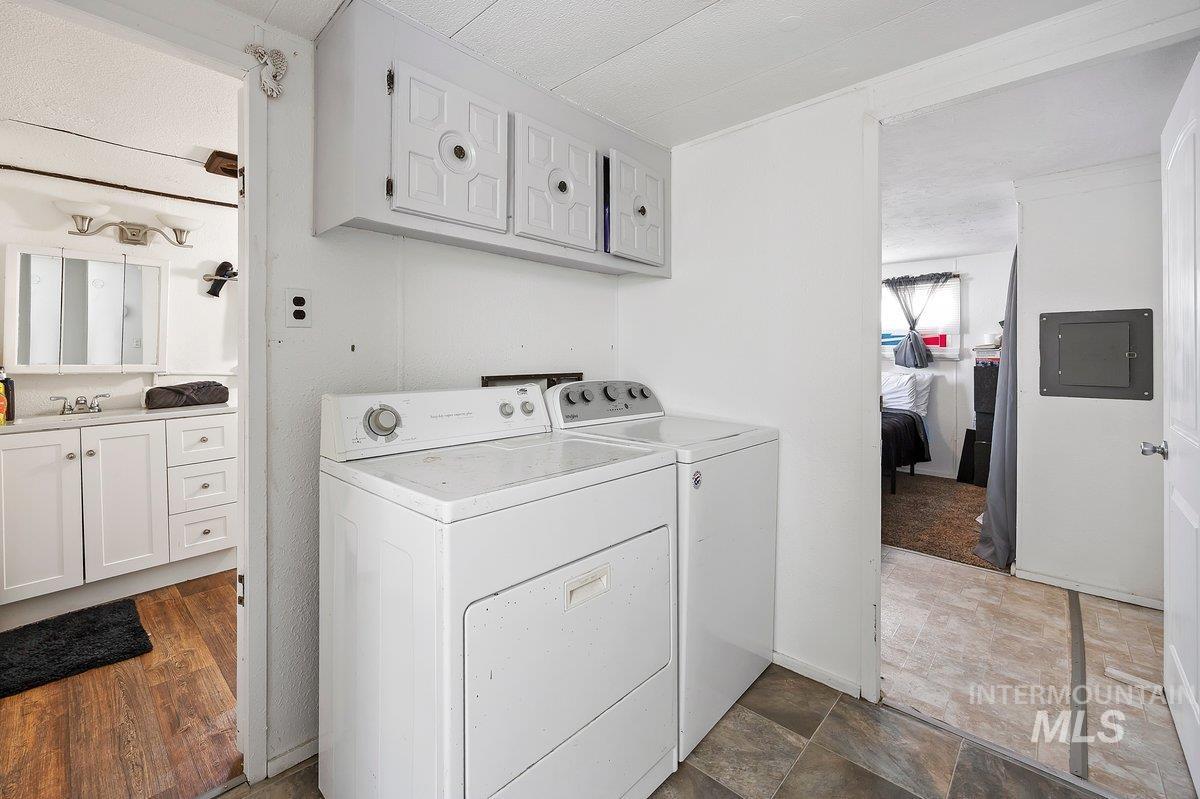 Laundry area with electric panel, independent washer and dryer, and a textured ceiling