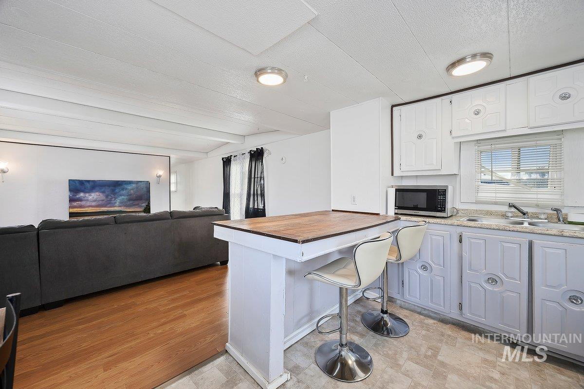 Kitchen featuring open floor plan, a breakfast bar, a peninsula, stainless steel microwave, and wooden counters