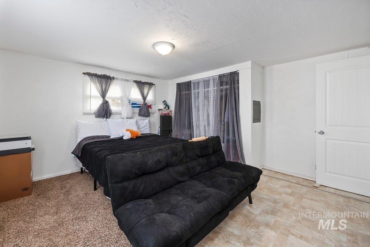 Bedroom with a textured ceiling and electric panel
