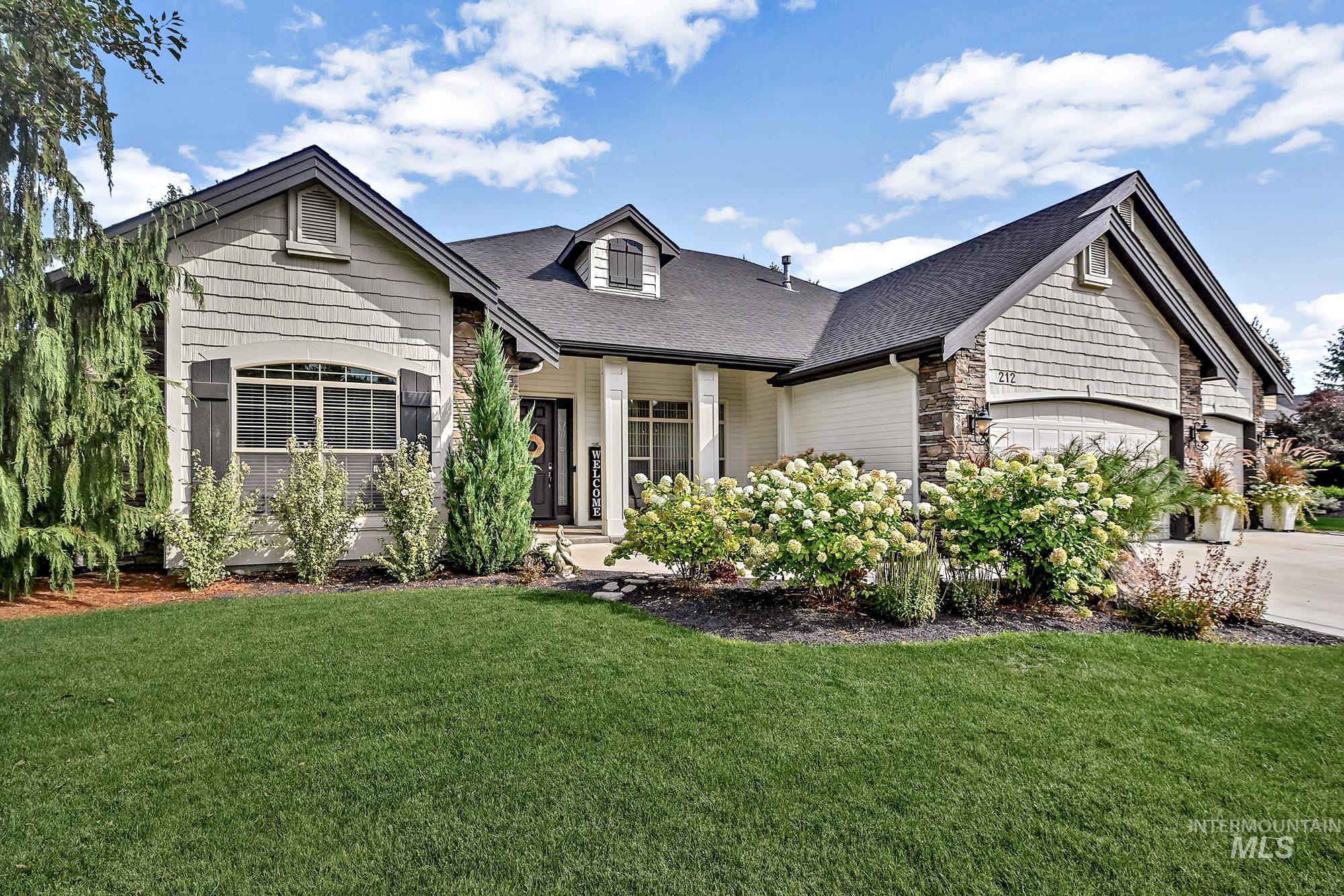 View of front facade featuring stone siding, a front yard, and roof with shingles