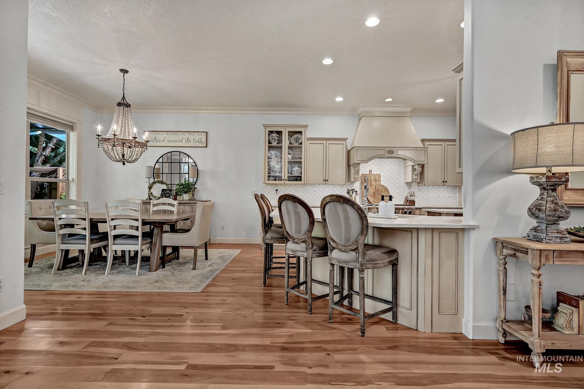 Kitchen featuring glass insert cabinets, pendant lighting, backsplash, a breakfast bar area, and a peninsula