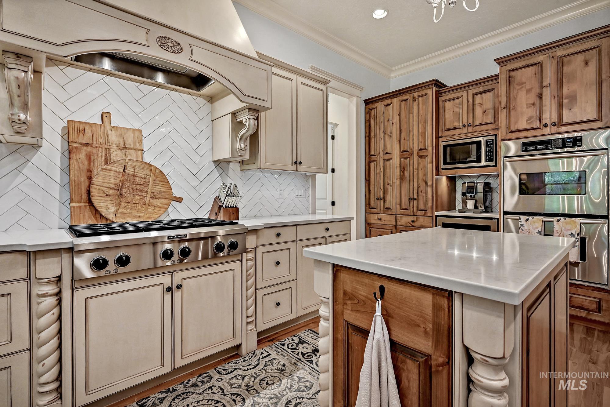 Kitchen with crown molding, stainless steel appliances, backsplash, brown cabinetry, and a center island