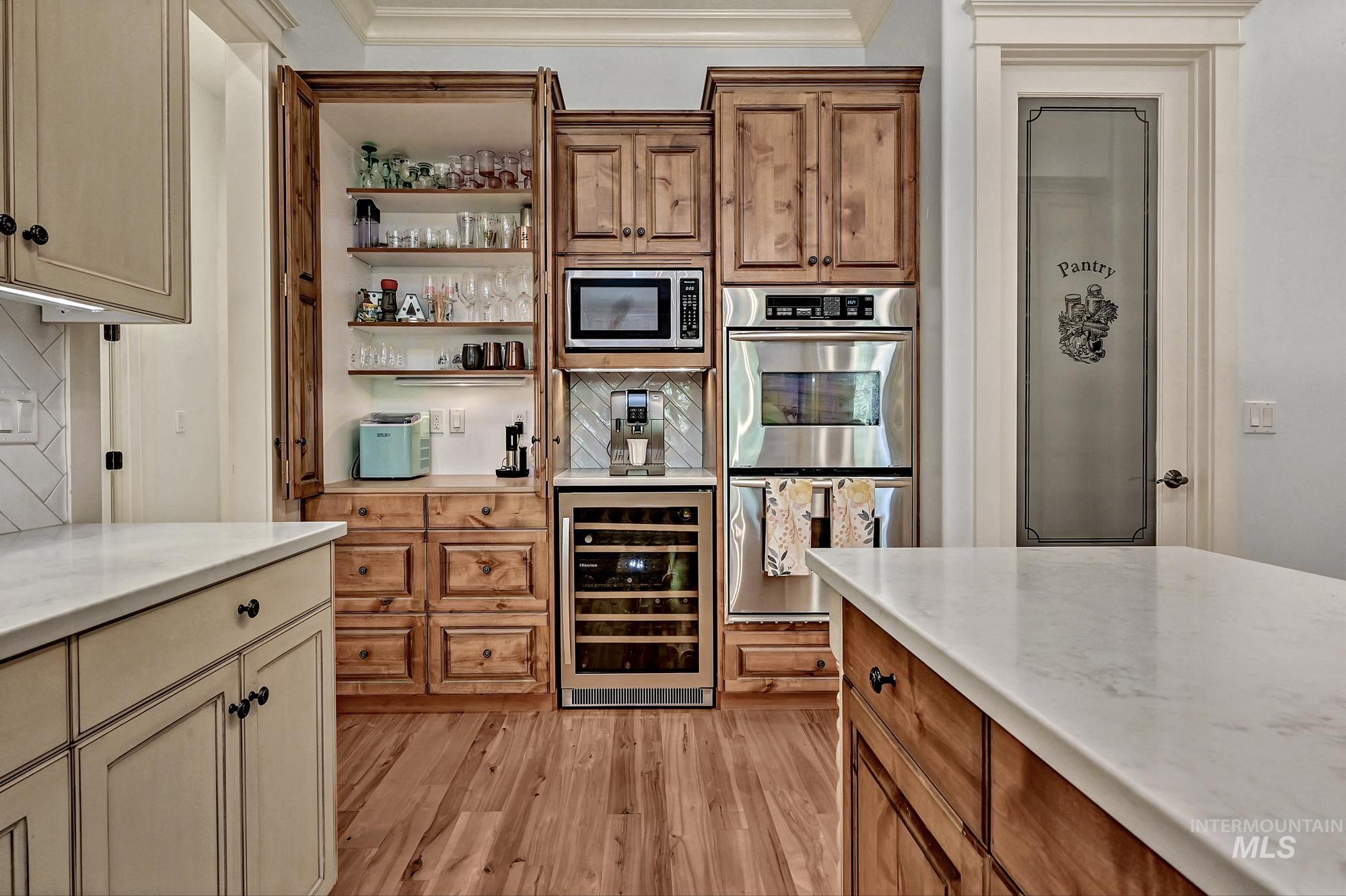 Kitchen featuring brown cabinets, wine cooler, open shelves, appliances with stainless steel finishes, and light wood-style floors