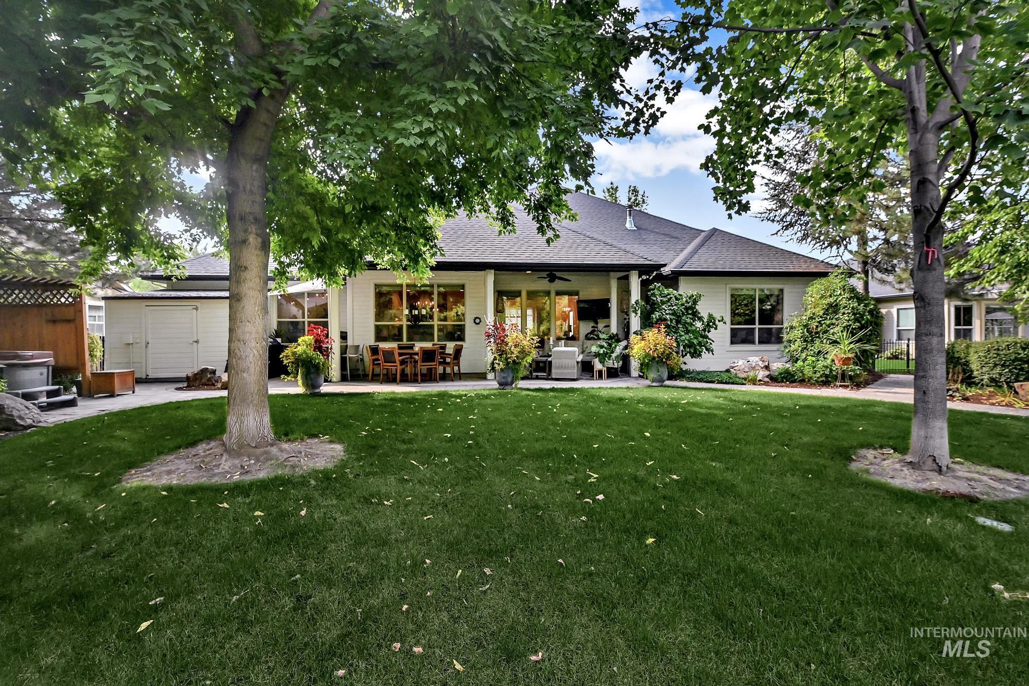 View of front facade with ceiling fan, roof with shingles, a patio, a storage unit, and a front yard