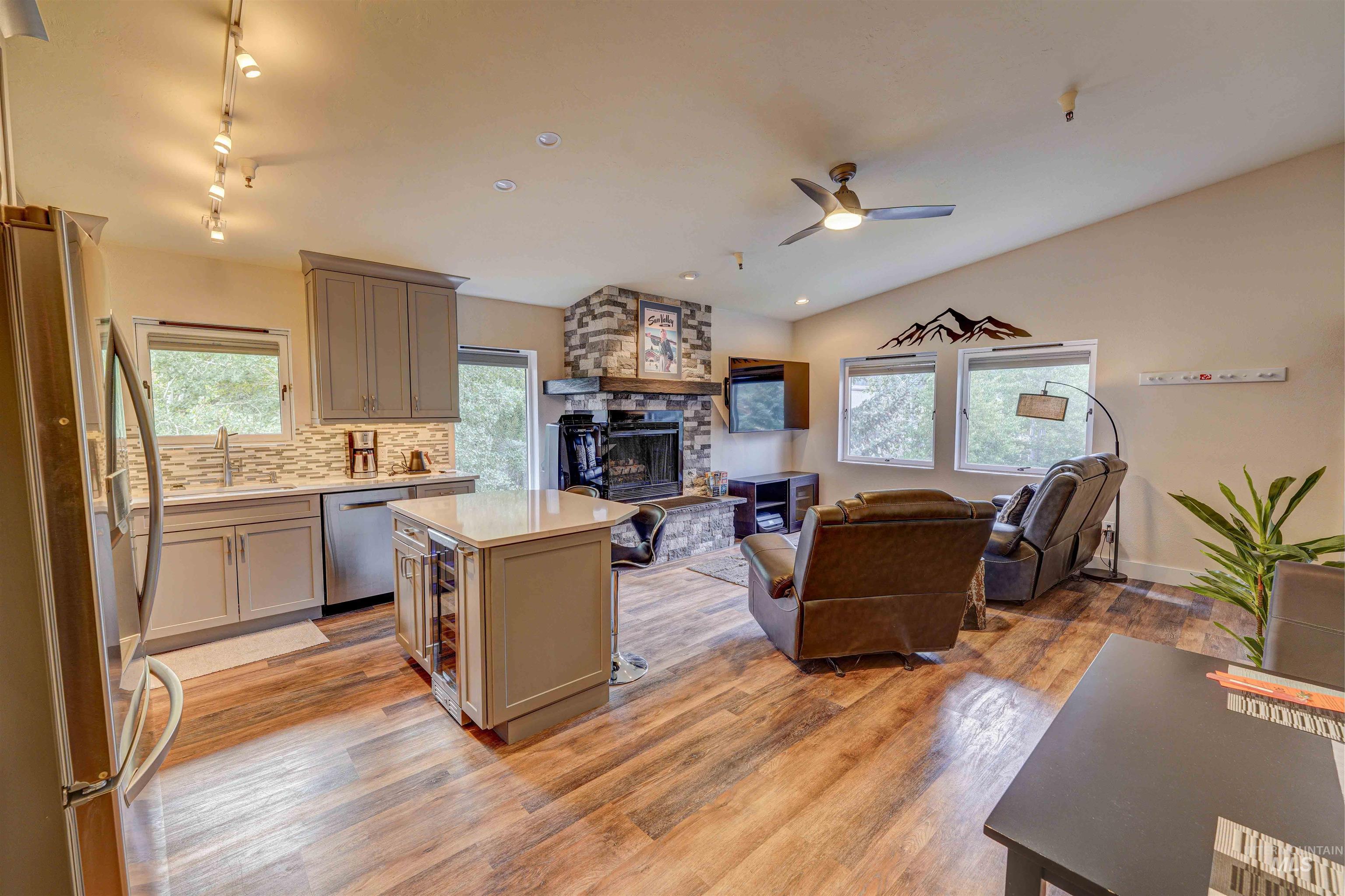 Kitchen featuring stainless steel appliances, backsplash, open floor plan, healthy amount of natural light, and light wood finished floors