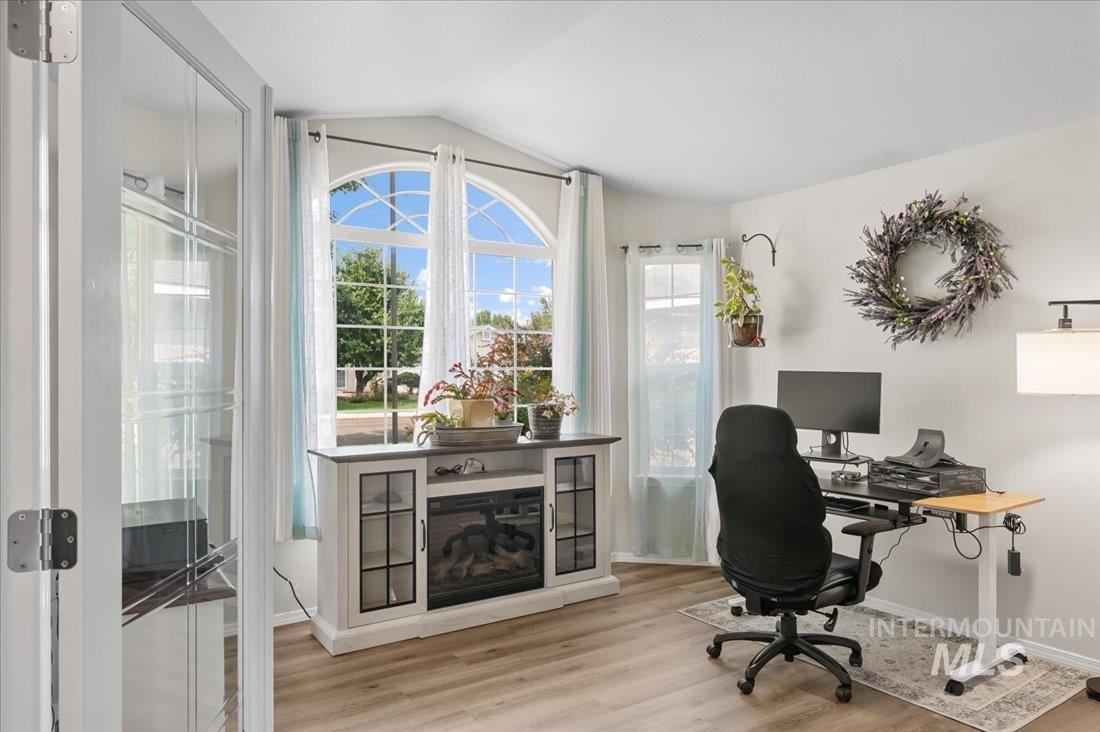 Office with light wood-style floors and lofted ceiling