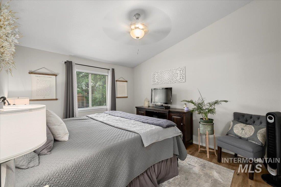 Bedroom featuring wood finished floors, lofted ceiling, and a ceiling fan