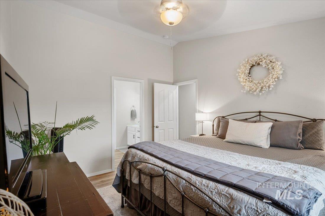 Bedroom with ensuite bath, wood finished floors, and a ceiling fan