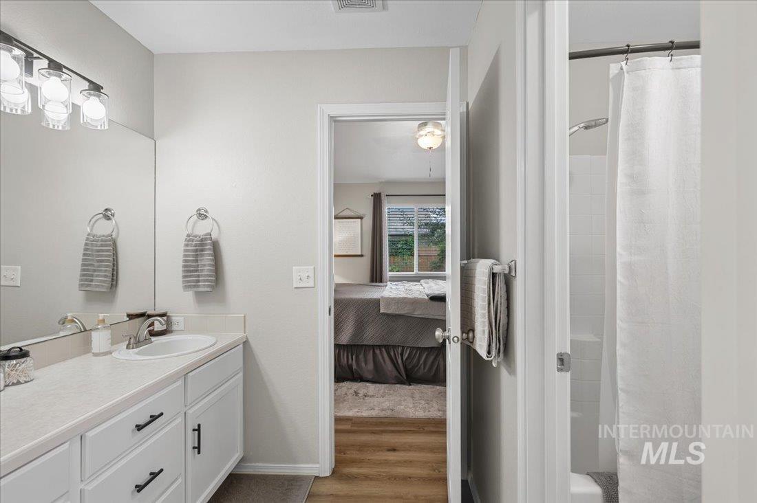 Bathroom featuring vanity, light wood-type flooring, connected bathroom, and shower / tub combo