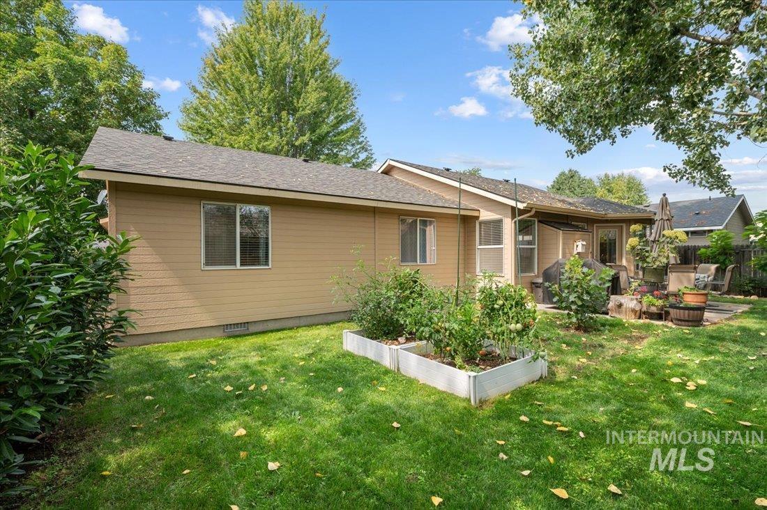 Rear view of house featuring a garden, a yard, and a shingled roof