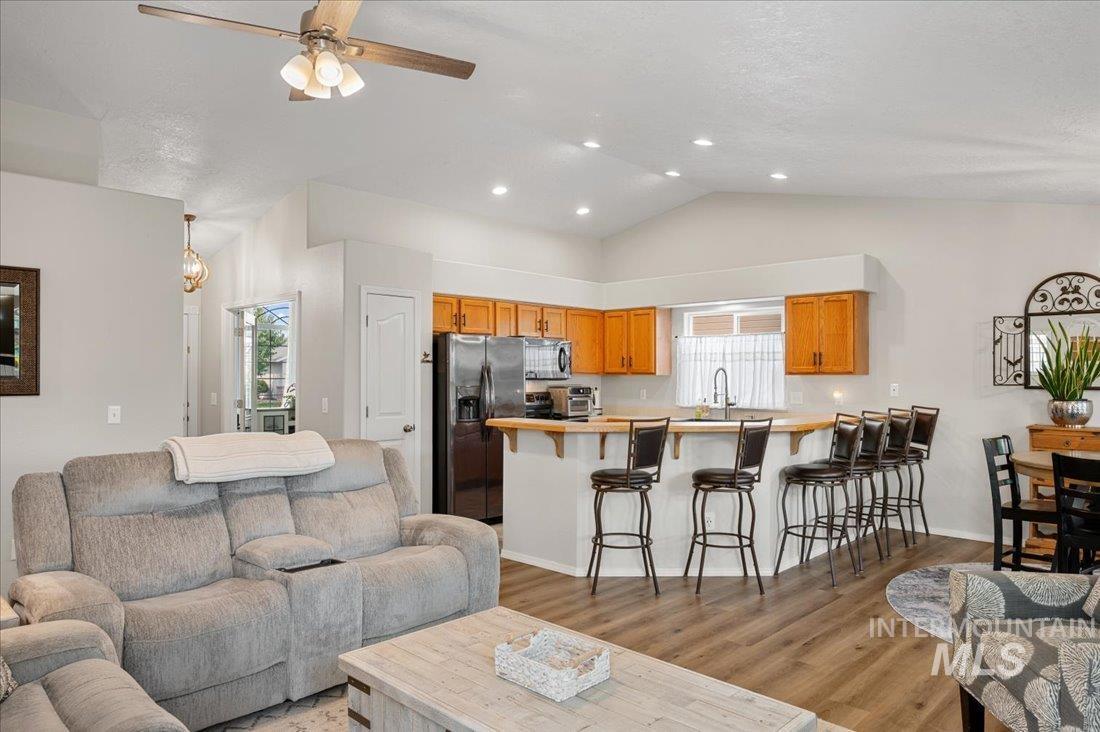 Living area with healthy amount of natural light, light wood finished floors, high vaulted ceiling, a ceiling fan, and recessed lighting