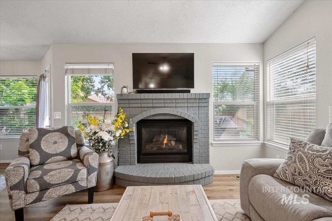 Living area with a textured ceiling, wood finished floors, and a brick fireplace