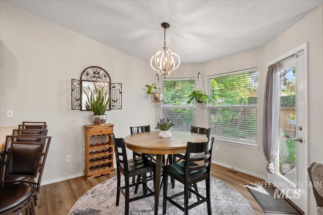 Dining room with wood finished floors, a textured ceiling, and a chandelier