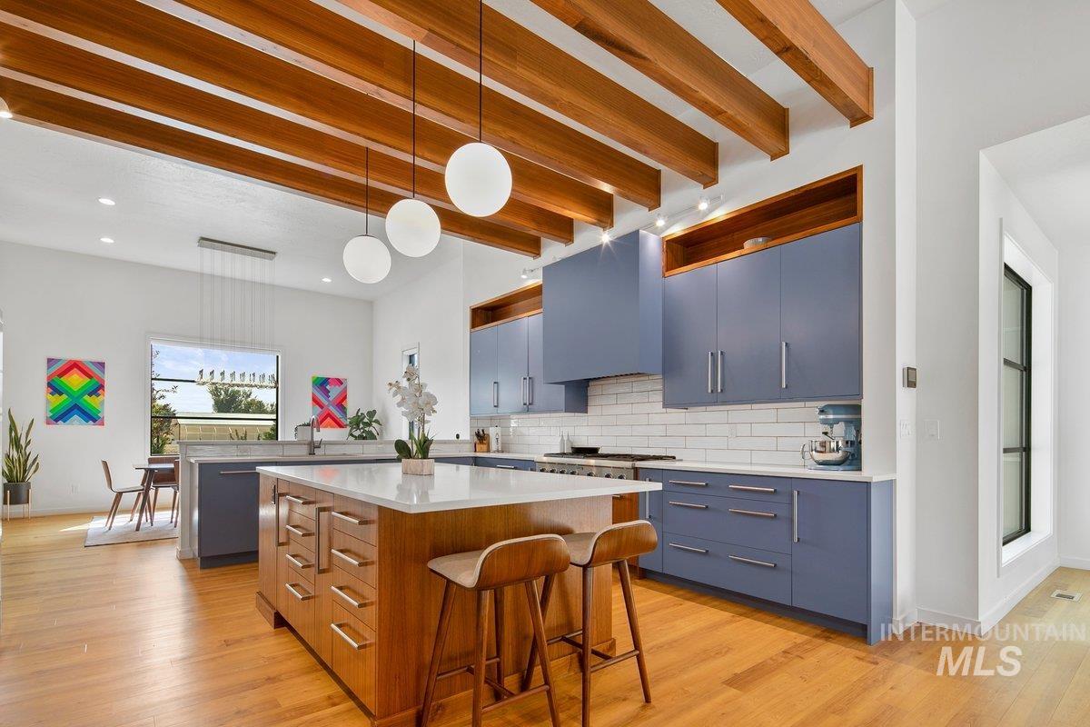 Kitchen featuring hanging light fixtures, a center island, beam ceiling, a breakfast bar, and light wood finished floors