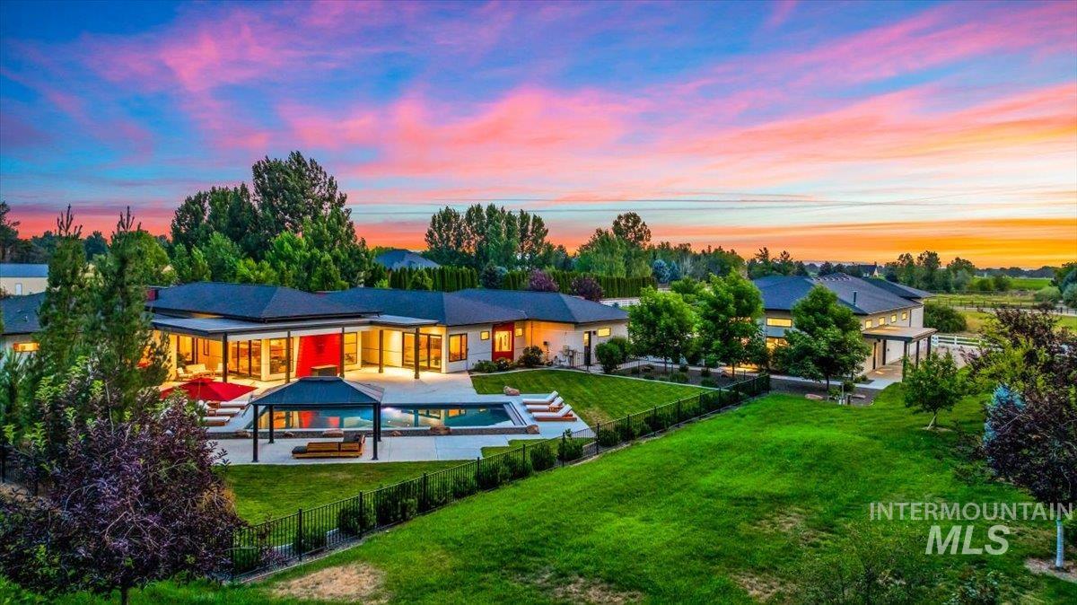 Back of house at dusk featuring a fenced backyard, a patio, and a gazebo