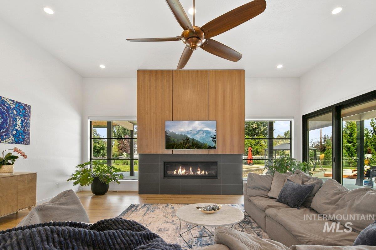 Living room featuring wood finished floors, a tiled fireplace, recessed lighting, and ceiling fan