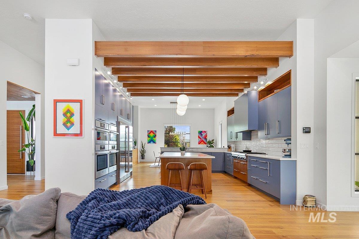 Kitchen with beam ceiling, open floor plan, light countertops, and light wood finished floors