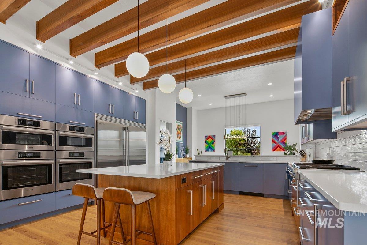 Kitchen with pendant lighting, a breakfast bar area, a center island, beamed ceiling, and light wood-style floors