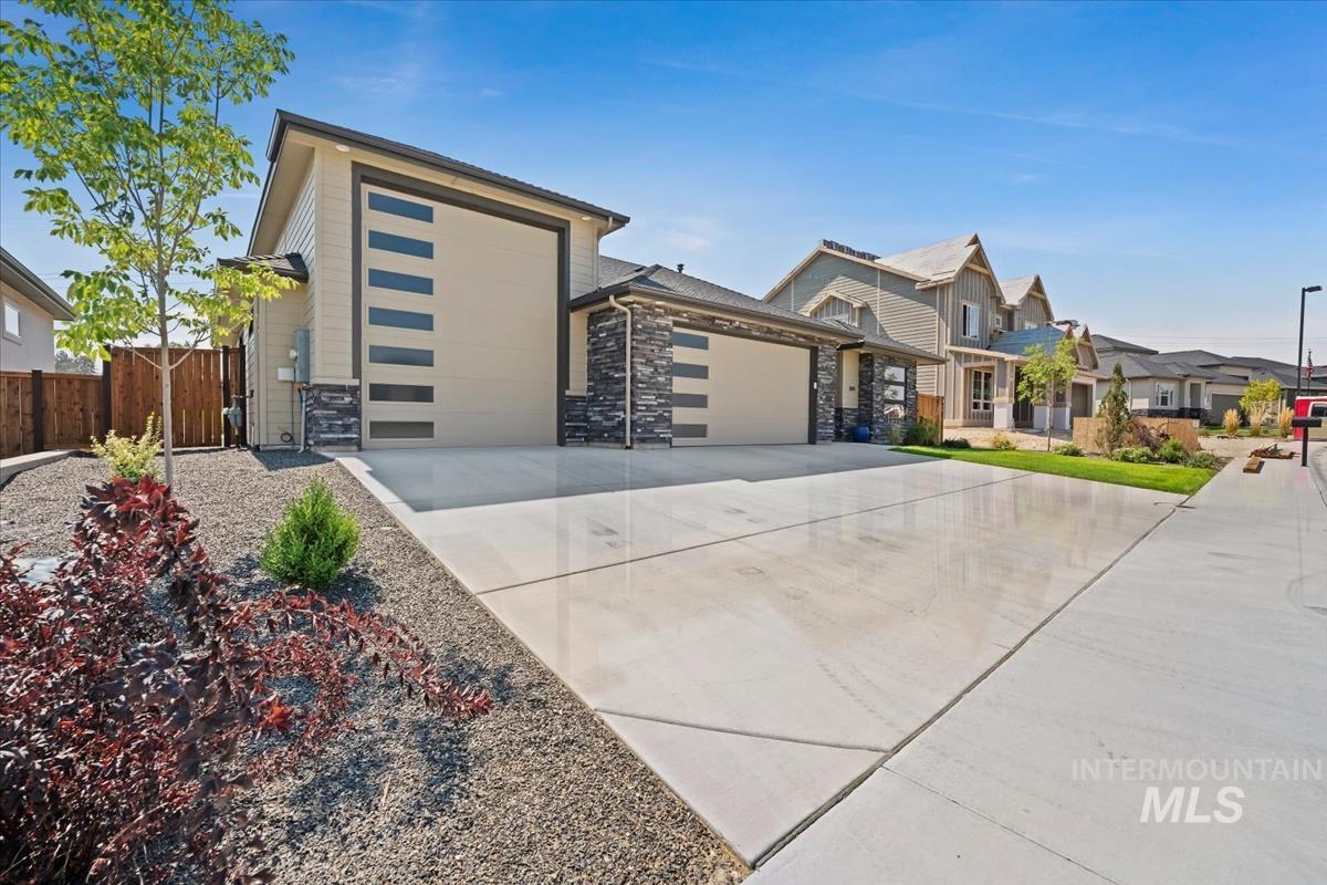 Contemporary home featuring a garage, concrete driveway, and stone siding