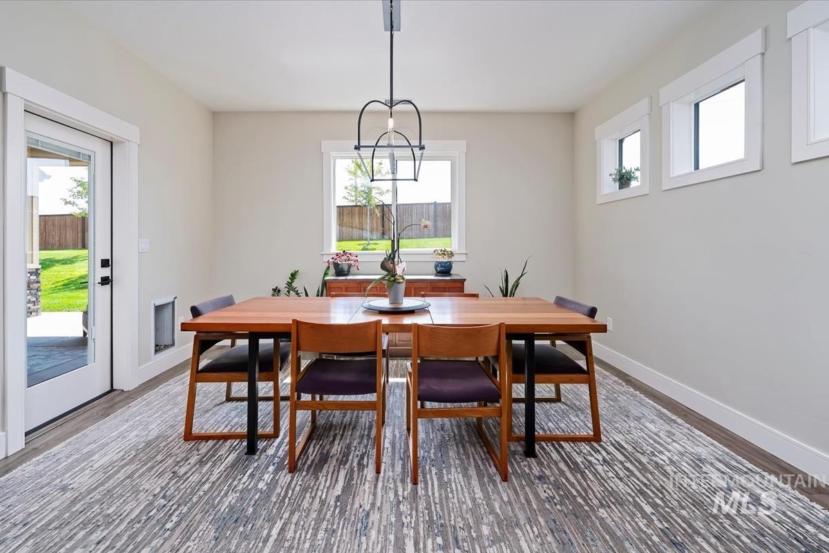 Dining room featuring healthy amount of natural light, wood finished floors, and a chandelier