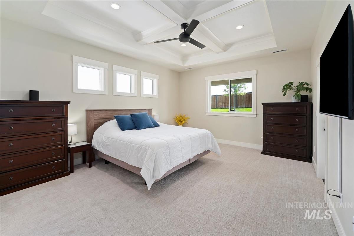 Bedroom with light colored carpet, beamed ceiling, coffered ceiling, a ceiling fan, and recessed lighting