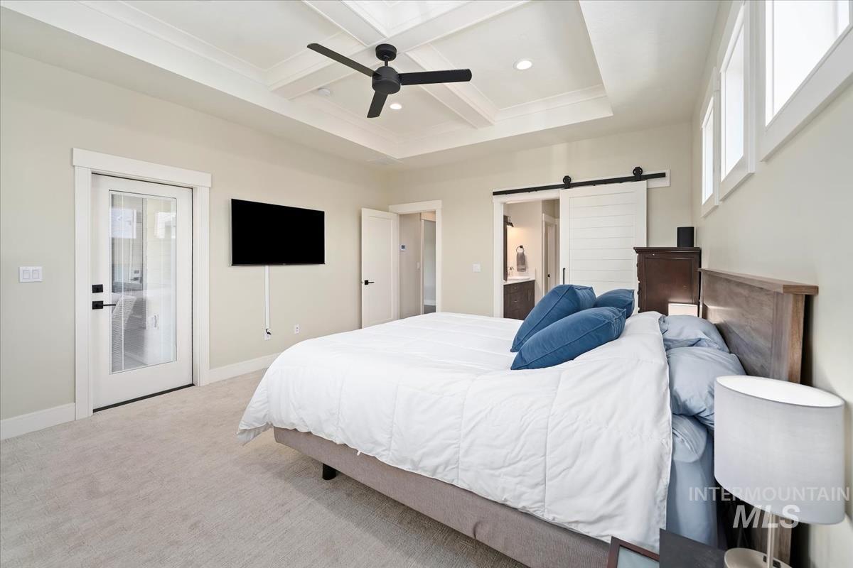 Bedroom featuring a barn door, carpet floors, beamed ceiling, connected bathroom, and multiple windows