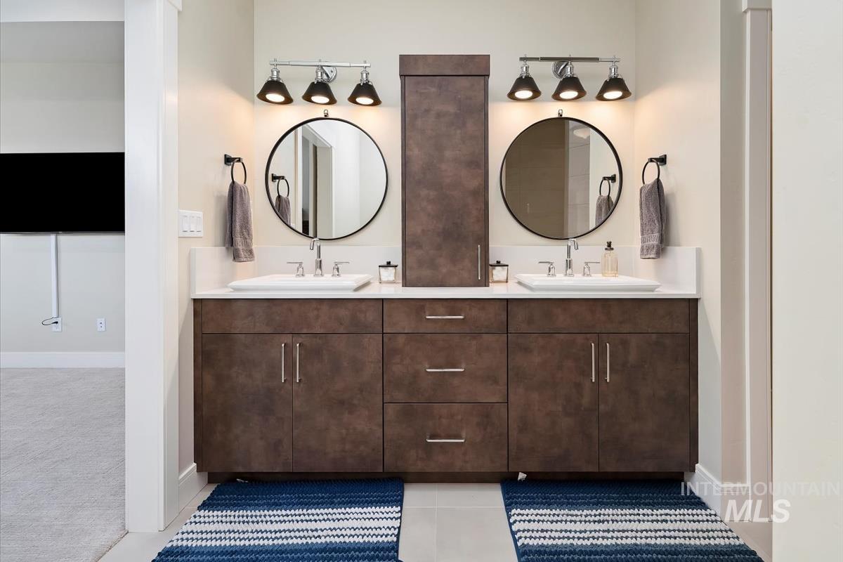 Full bath featuring double vanity and light tile patterned floors