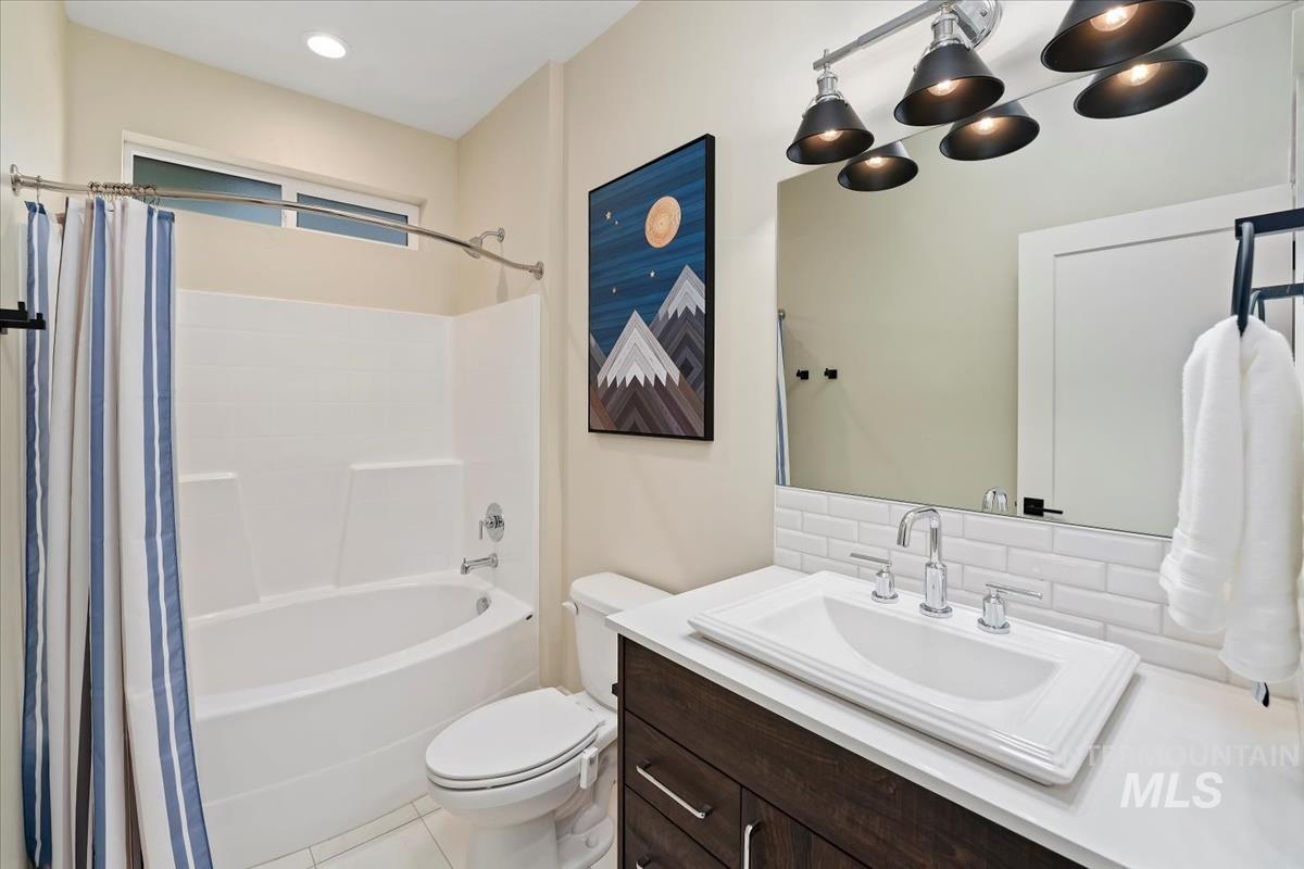 Full bath featuring shower / tub combo, vanity, light tile patterned floors, and backsplash