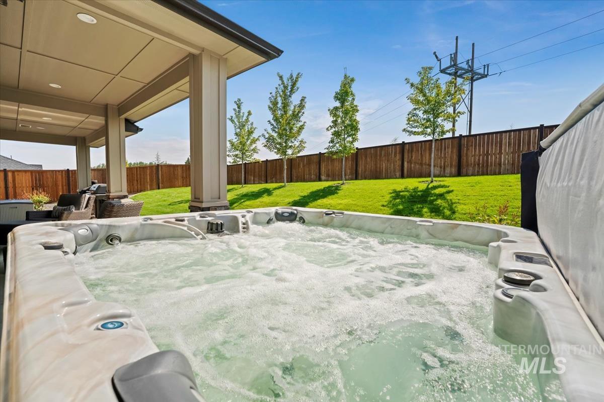 Fenced backyard with a hot tub and a patio area