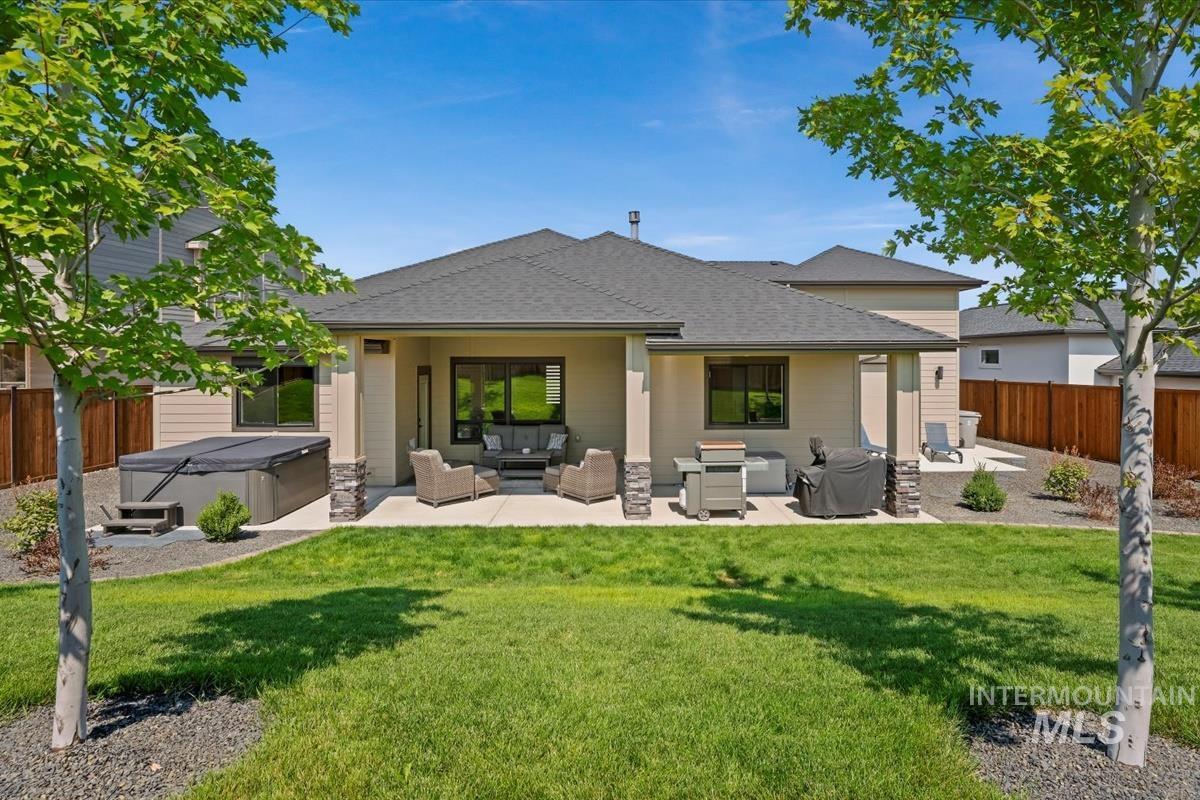 Back of house with outdoor lounge area, a hot tub, a fenced backyard, a patio, and roof with shingles