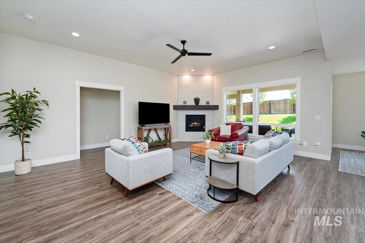 Living room featuring a large fireplace, wood finished floors, recessed lighting, and ceiling fan
