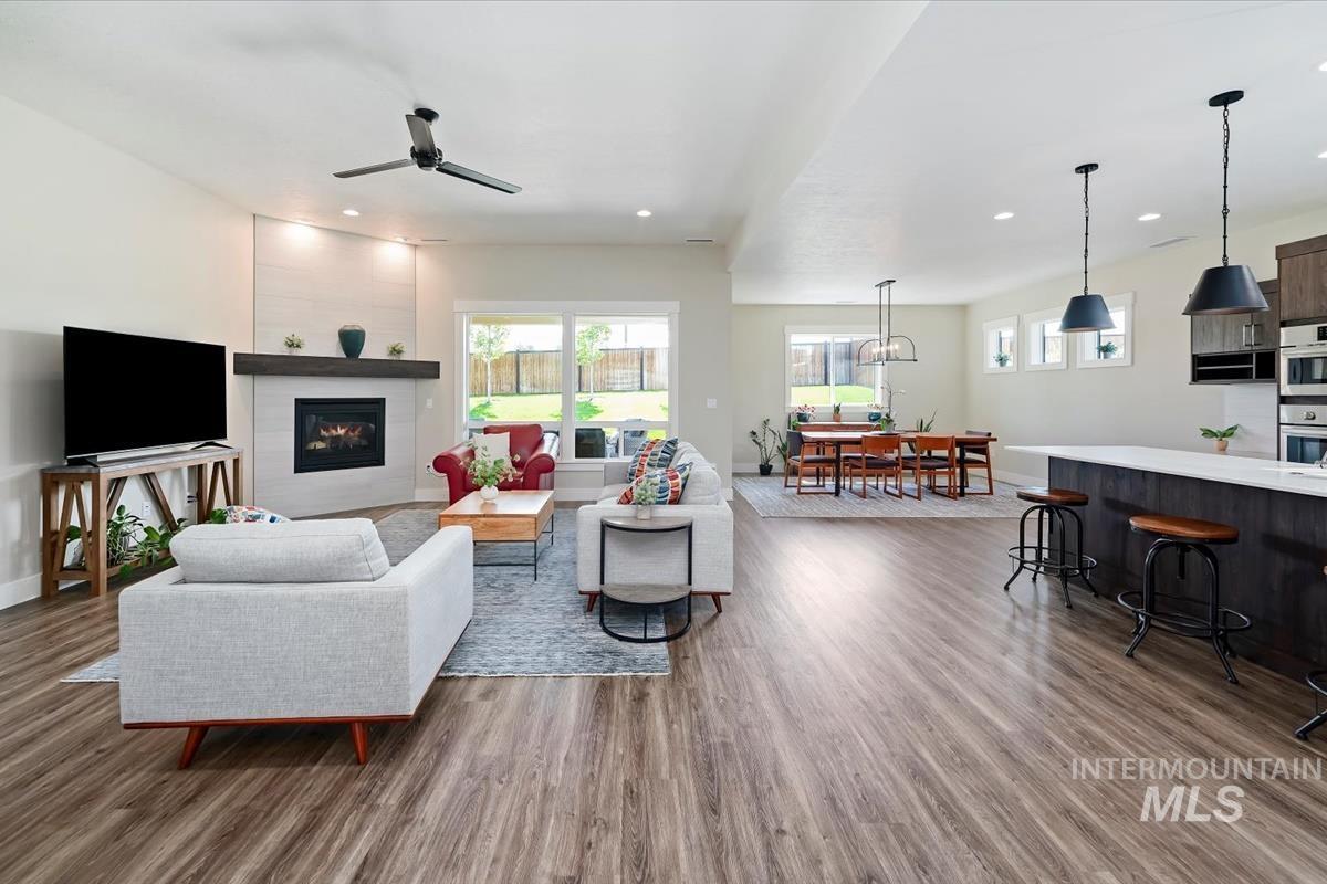 Living room with light wood-style flooring, a fireplace, recessed lighting, and ceiling fan