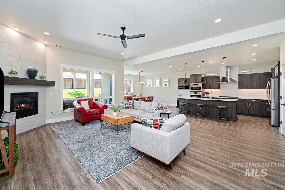 Living area featuring light wood-type flooring, ceiling fan, a tiled fireplace, and recessed lighting