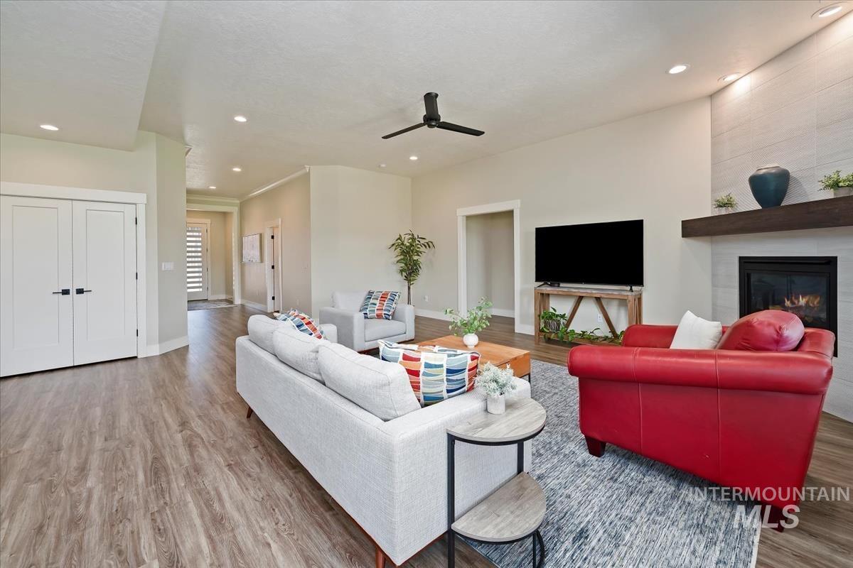 Living room featuring recessed lighting, light wood finished floors, a fireplace, and a ceiling fan