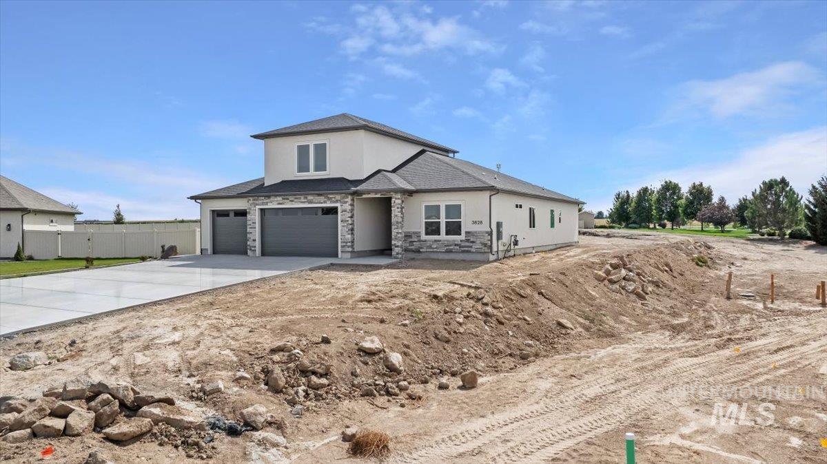 View of front facade featuring concrete driveway, stucco siding, stone siding, and a garage