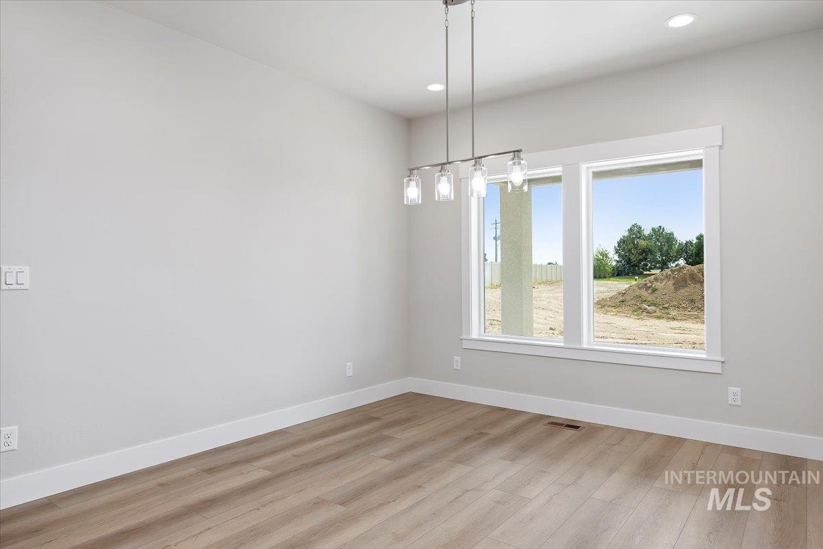 Unfurnished dining area featuring light wood-type flooring, recessed lighting, and a chandelier