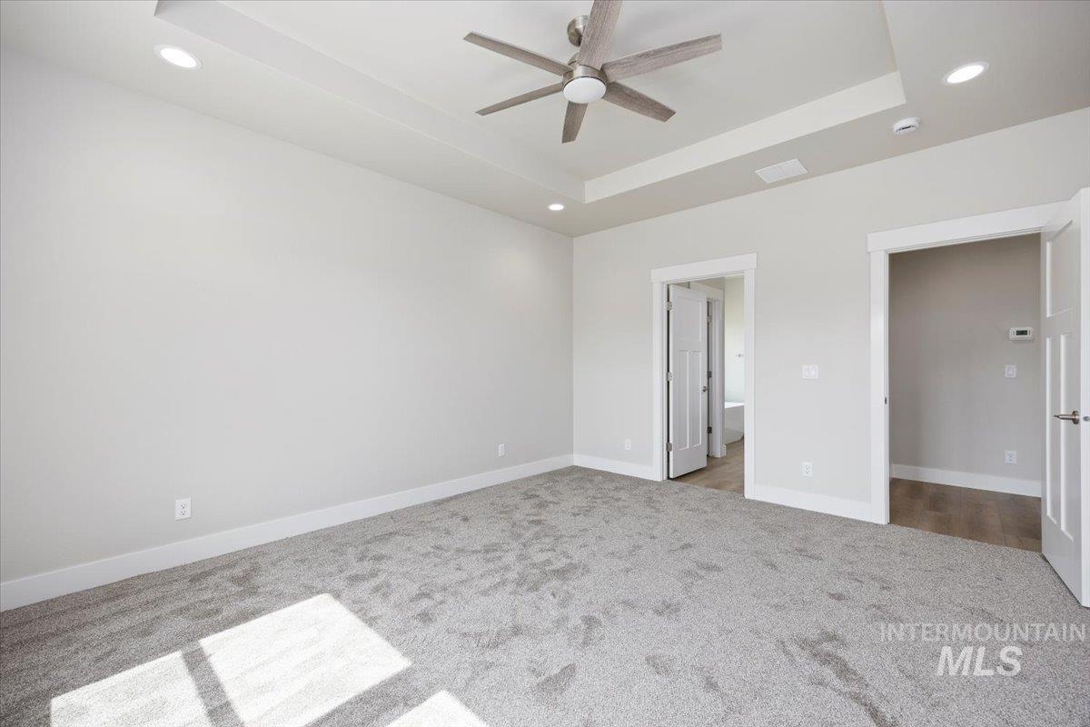 Unfurnished bedroom with a tray ceiling, recessed lighting, carpet, and a ceiling fan