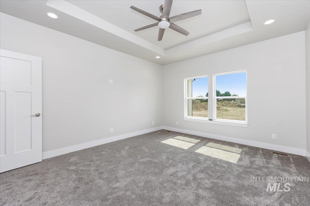 Carpeted empty room featuring a tray ceiling, recessed lighting, and ceiling fan