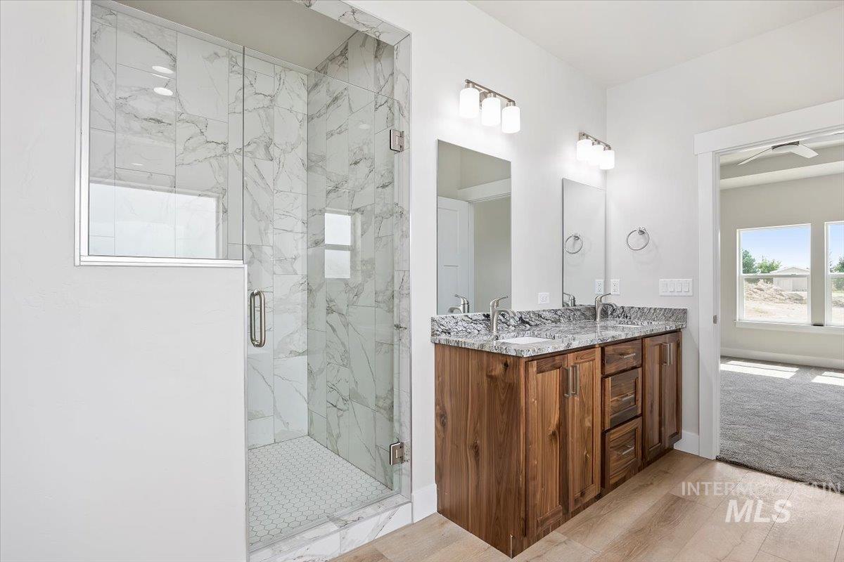 Bathroom with a marble finish shower, double vanity, and light wood-type flooring