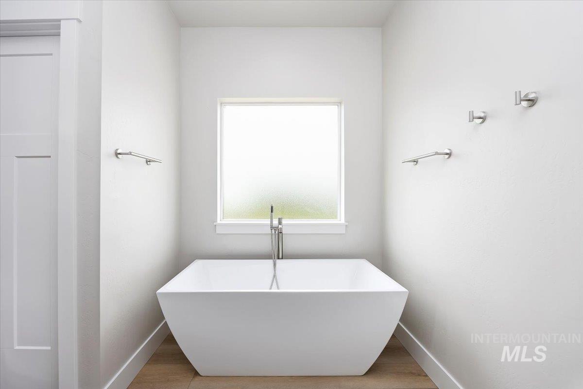 Full bathroom with a freestanding tub and light wood-style flooring