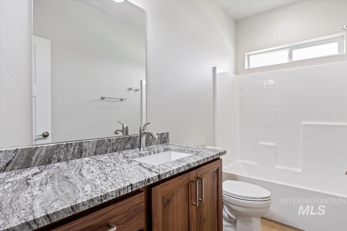 Full bathroom featuring vanity, bathtub / shower combination, and a textured wall