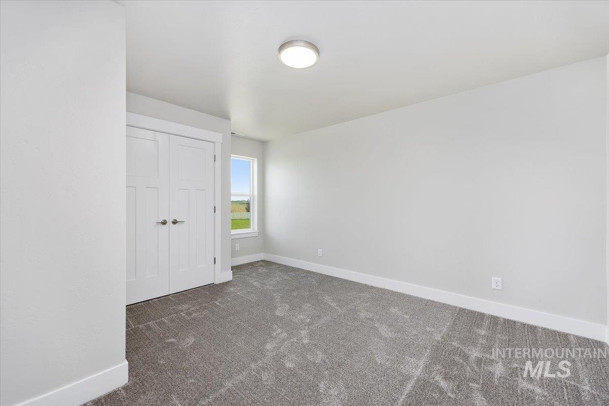 Unfurnished bedroom with dark carpet and a closet